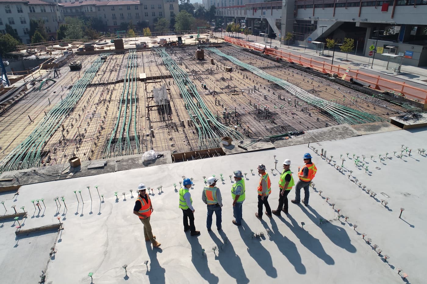 Villa roof — polyurethane field coat in progress. Construction crew applying protective coating on a concrete roof deck
